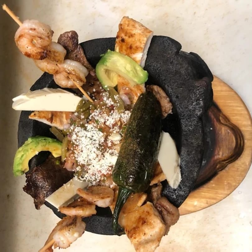 Si Señor 2's molcajete with grilled meats, shrimp, avocado, cheese, and a large poblano pepper.